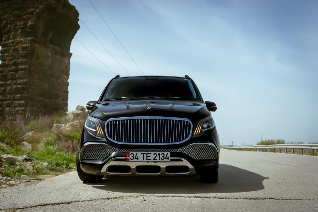 Schwarzes Luxus-SUV vor historischer Steinarchitektur auf einer Straße.